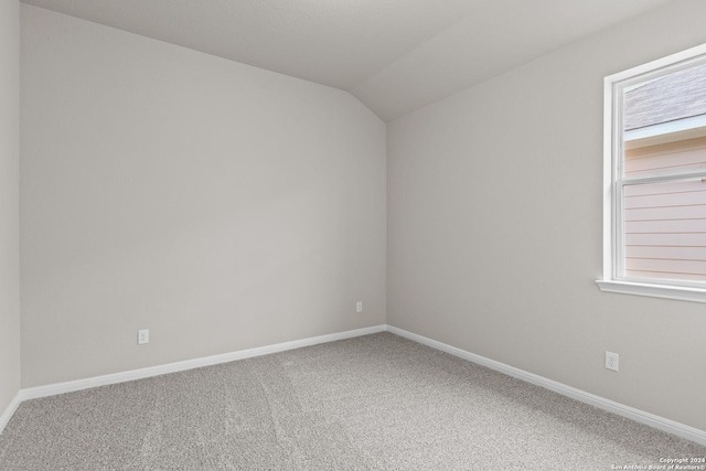 carpeted spare room featuring vaulted ceiling