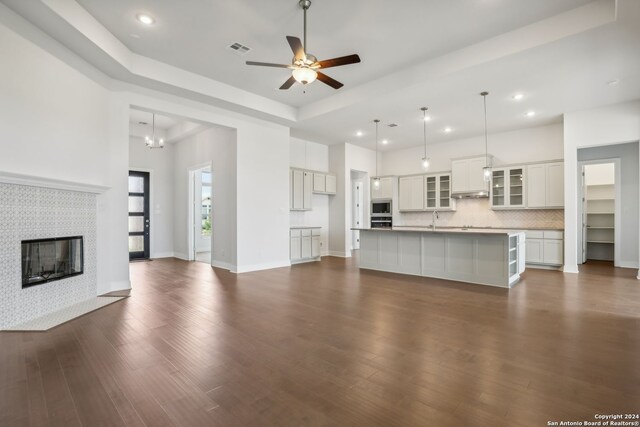 unfurnished living room featuring ceiling fan, dark hardwood / wood-style flooring, sink, and a tile fireplace