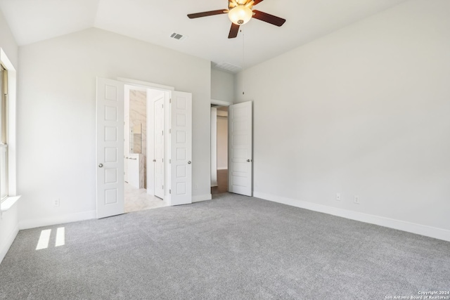 unfurnished bedroom with vaulted ceiling, connected bathroom, light colored carpet, and ceiling fan