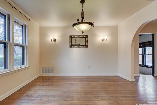 empty room with a wealth of natural light, ornamental molding, and hardwood / wood-style floors