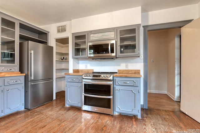 kitchen featuring stainless steel appliances, butcher block counters, and dark hardwood / wood-style floors