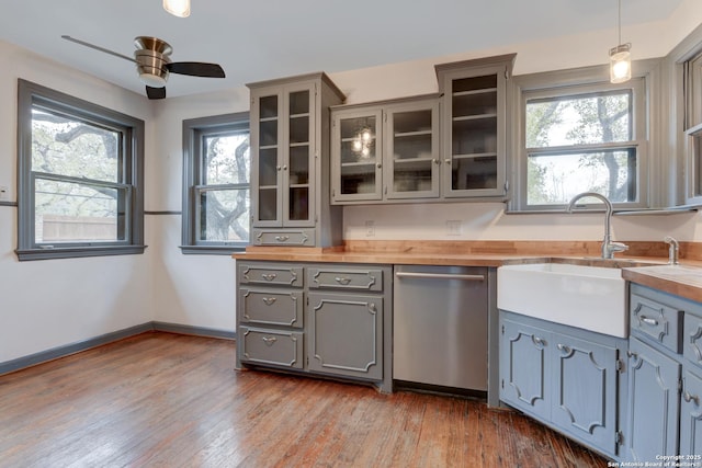 kitchen featuring decorative light fixtures, sink, butcher block countertops, stainless steel dishwasher, and gray cabinetry