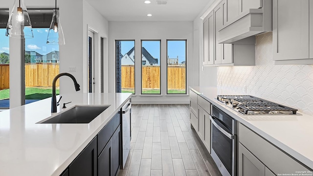 kitchen with stainless steel appliances, light countertops, a sink, and decorative backsplash
