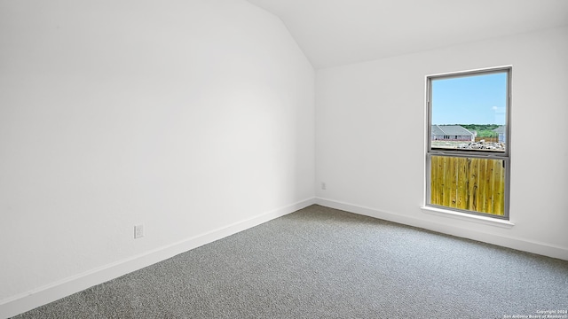 spare room featuring carpet flooring and lofted ceiling