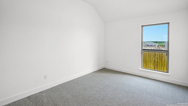 spare room featuring baseboards, carpet flooring, and lofted ceiling