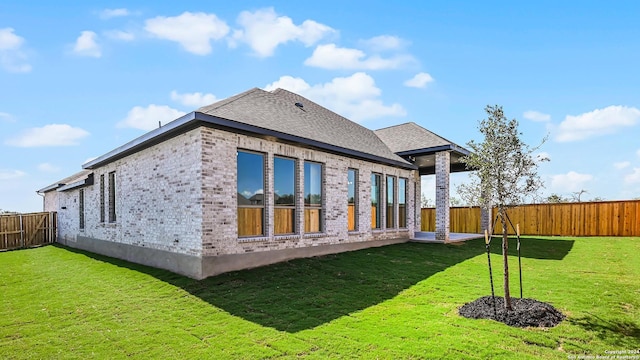 back of property with a lawn, a fenced backyard, and brick siding