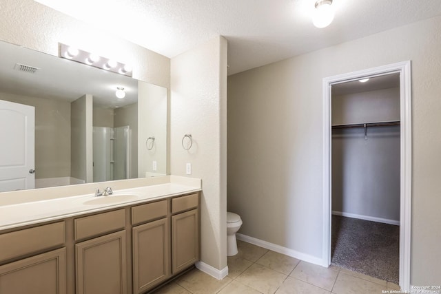 bathroom with tile patterned flooring, vanity, toilet, and a textured ceiling