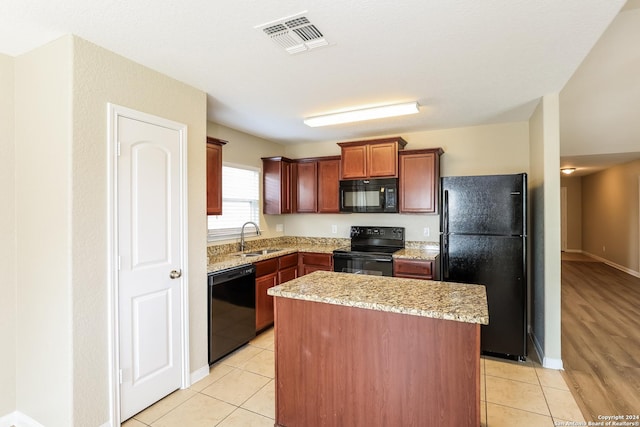 kitchen with sink, a center island, black appliances, and light tile patterned floors