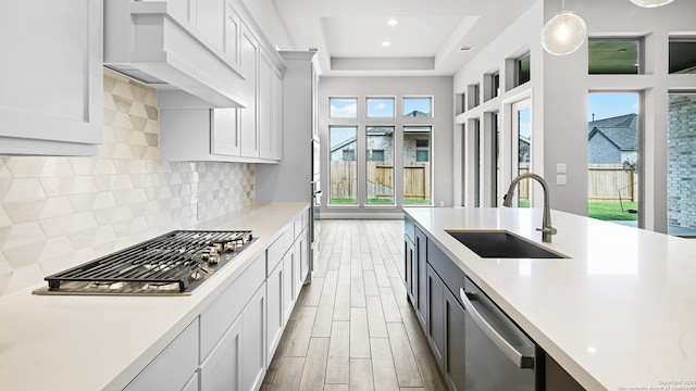 kitchen featuring premium range hood, sink, tasteful backsplash, decorative light fixtures, and stainless steel appliances