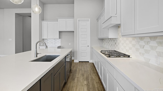 kitchen featuring stainless steel appliances, sink, decorative light fixtures, hardwood / wood-style flooring, and white cabinets