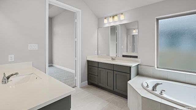 bathroom with tile patterned flooring, a relaxing tiled tub, vanity, and vaulted ceiling