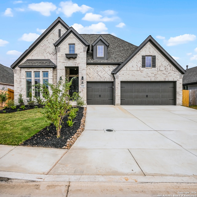 french country home with a front yard and a garage