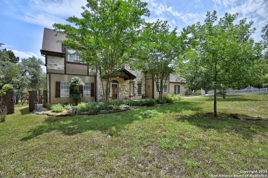 view of front of home with stone siding, a front yard, fence, and stucco siding