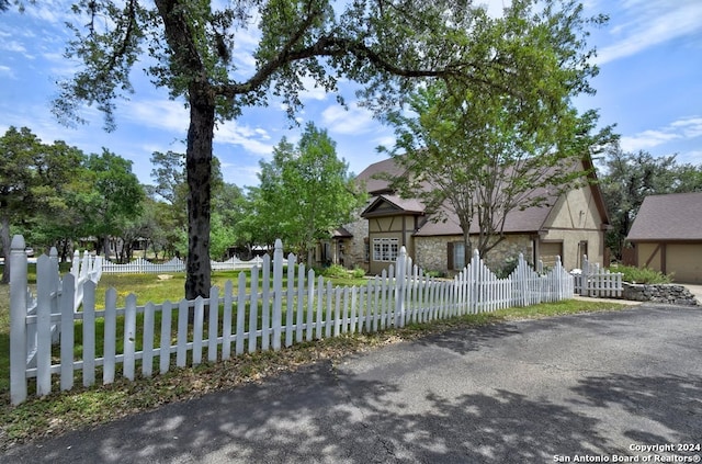 english style home with a fenced front yard and stone siding