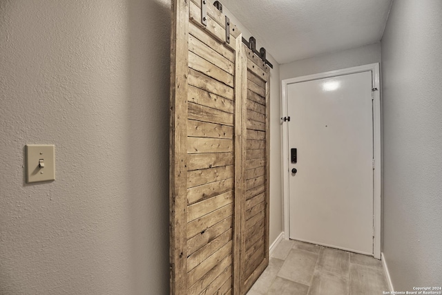 doorway with a barn door, light wood-style flooring, and a textured wall