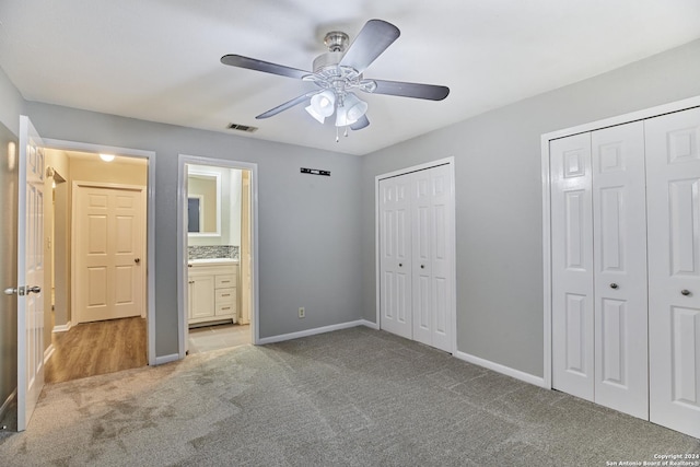 unfurnished bedroom featuring light carpet, ceiling fan, multiple closets, and ensuite bathroom