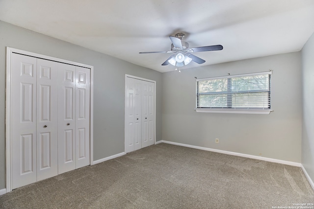 unfurnished bedroom with ceiling fan, multiple closets, and carpet