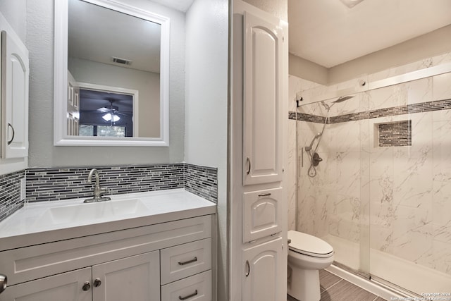 bathroom with ceiling fan, a tile shower, toilet, tasteful backsplash, and vanity