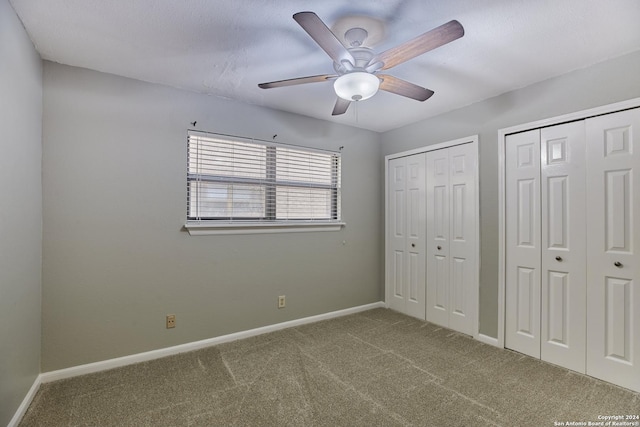 unfurnished bedroom featuring multiple closets, ceiling fan, and carpet