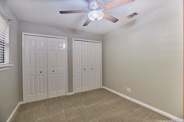 unfurnished bedroom with ceiling fan, carpet flooring, and two closets