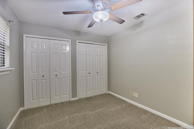 unfurnished bedroom featuring carpet flooring, two closets, and ceiling fan