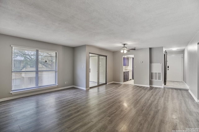 unfurnished living room with dark wood-type flooring, a textured ceiling, and ceiling fan