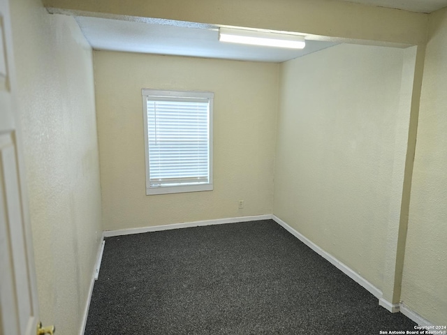 unfurnished room with dark colored carpet and baseboards
