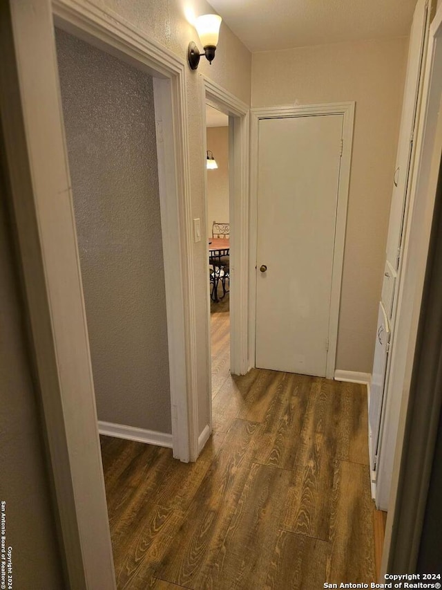 corridor with baseboards and wood finished floors