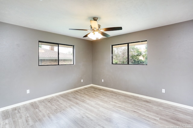 spare room featuring light wood-type flooring, a wealth of natural light, and ceiling fan