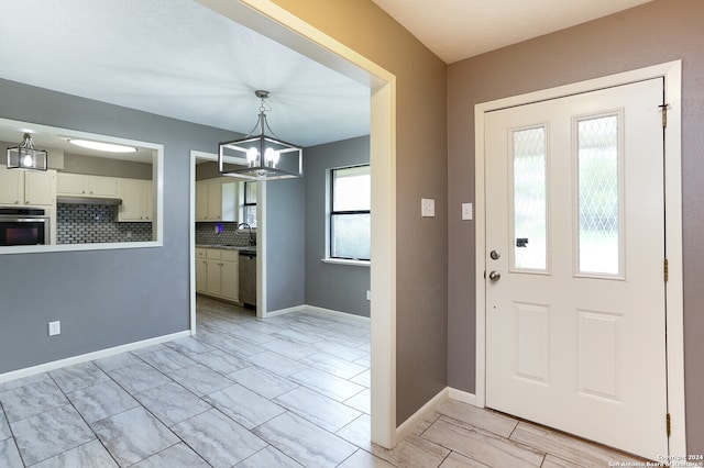 tiled entrance foyer featuring a notable chandelier and sink