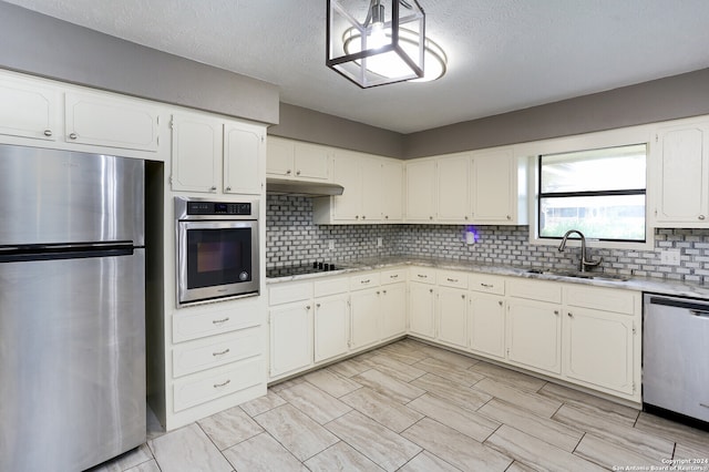 kitchen featuring tasteful backsplash, white cabinets, sink, a textured ceiling, and appliances with stainless steel finishes