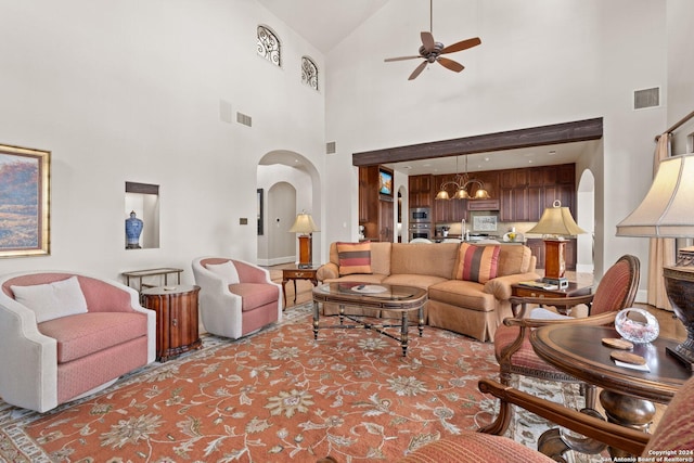 living room with sink, ceiling fan with notable chandelier, and a high ceiling