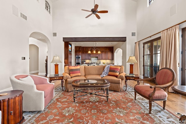 living room featuring ceiling fan, plenty of natural light, and a towering ceiling