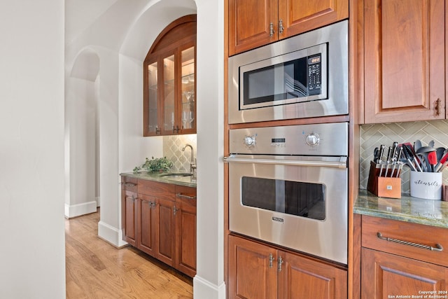 kitchen with decorative backsplash, light stone countertops, sink, and appliances with stainless steel finishes