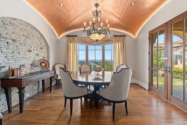 dining area with french doors, brick ceiling, hardwood / wood-style flooring, a notable chandelier, and lofted ceiling