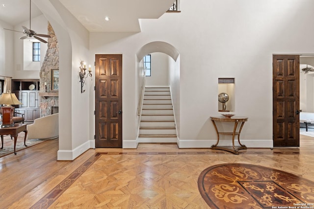 entryway with a fireplace, a high ceiling, and ceiling fan