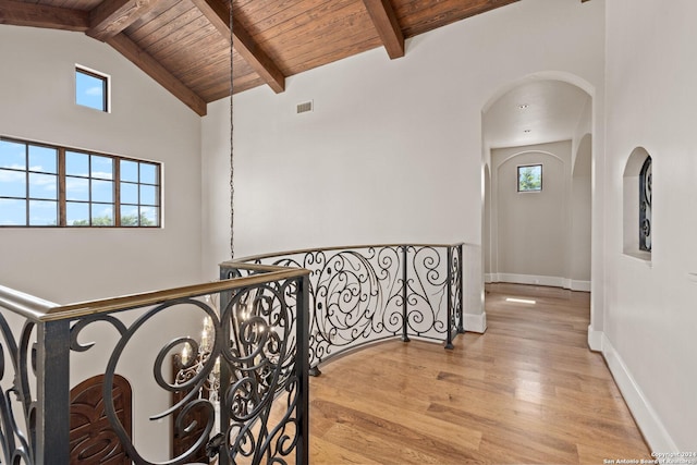 hall with beam ceiling, wooden ceiling, an inviting chandelier, light hardwood / wood-style flooring, and high vaulted ceiling