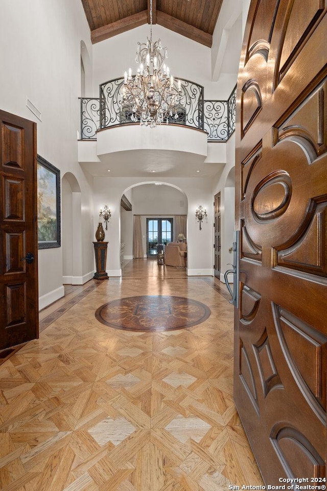 entryway featuring a high ceiling, french doors, a notable chandelier, beam ceiling, and wood ceiling