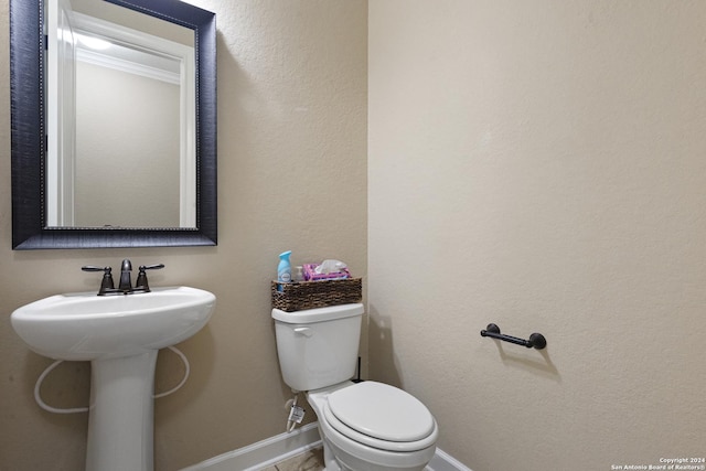 bathroom with toilet, sink, and crown molding