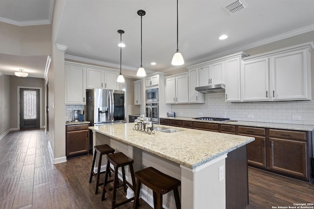 kitchen with stainless steel appliances, white cabinets, decorative light fixtures, backsplash, and a kitchen island with sink