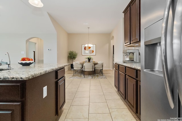 kitchen featuring sink, an inviting chandelier, stainless steel refrigerator with ice dispenser, a kitchen island with sink, and light tile patterned floors