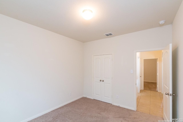 unfurnished bedroom with light carpet and a closet