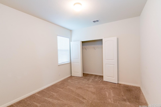 unfurnished bedroom with light carpet and a closet