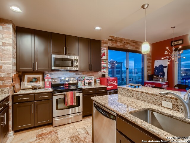 215 Center St Unit 307, San Antonio, TX 78202 - kitchen featuring stainless steel appliances, a sink, hanging light fixtures, light stone countertops, and backsplash