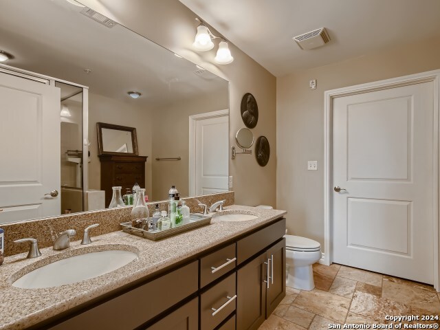 215 Center St Unit 307, San Antonio, TX 78202 - bathroom featuring stone tile flooring, toilet, and double vanity
