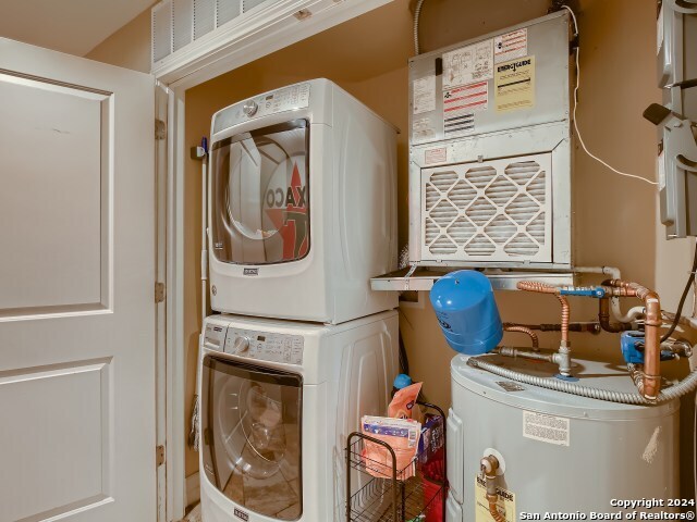 215 Center St Unit 307, San Antonio, TX 78202 - clothes washing area featuring water heater, stacked washer and clothes dryer, and heating unit