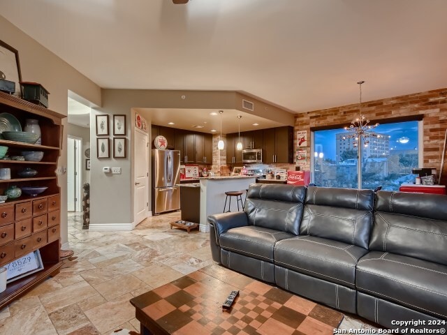 215 Center St Unit 307, San Antonio, TX 78202 - living room with stone tile flooring, a chandelier, and baseboards