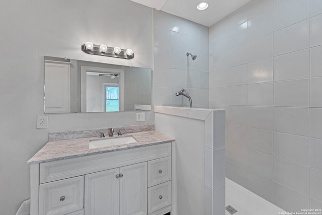 bathroom with tiled shower, vanity, and ceiling fan