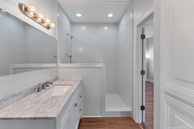 bathroom with a tile shower, wood-type flooring, and oversized vanity