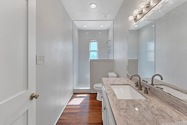 bathroom featuring tiled shower, hardwood / wood-style floors, toilet, and large vanity